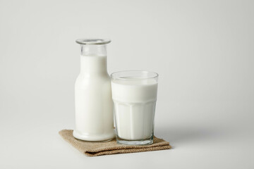 A glass and bottle of milk of milk on a white background