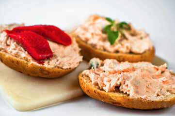 3 canapés with salmon spread with fresh cheese on board.