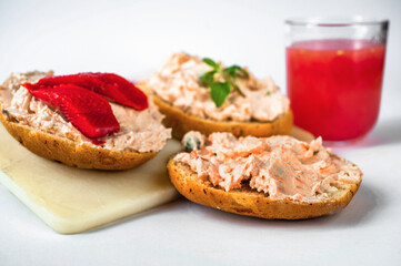 3 canapés with salmon spread with fresh cheese on board, glass of juice .