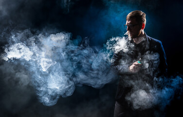Man in smoke from vaping. Unrecognizable vaper guy. Human vaping while standing in dark. Vaper...