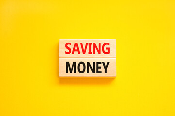 Saving money symbol. Concept words Saving money on wooden blocks on a beautiful yellow table yellow background. Business, support and saving money concept. Copy space.