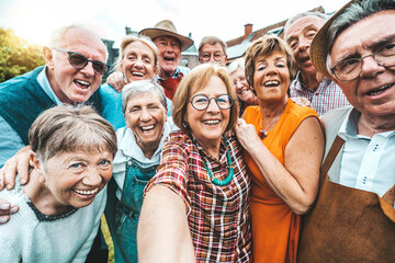 Happy group of senior people smiling at camera outdoors - Aged friends taking selfie pic with smart mobile phone device - Life style concept with pensioners having fun together on summer holiday