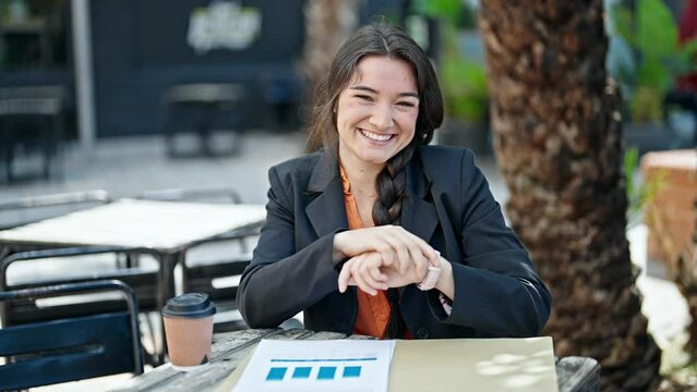 Young beautiful hispanic woman business worker looking watch smiling at coffee shop terrace