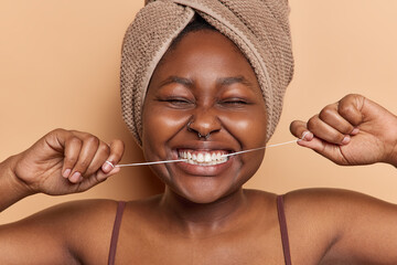 Woman with piercing in nose keeps mouth opened as she skillfully removes food with dental floss...