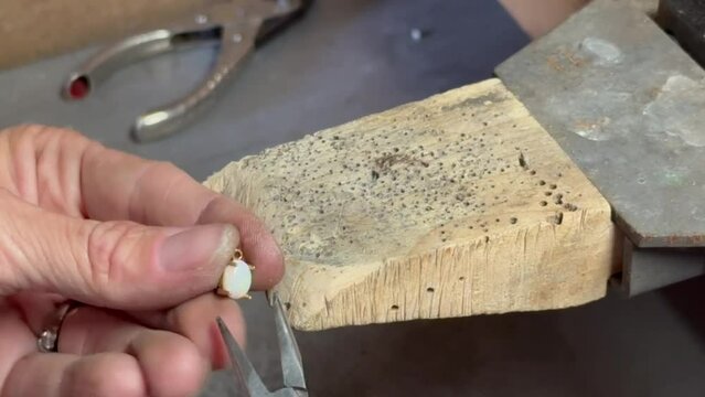 Jeweler setting an oval gemstone- Benchpin close up with pliers
