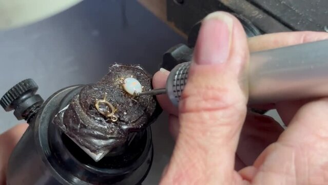 Jeweler rounding out prongs - stone setting of Opal cabochon close-up