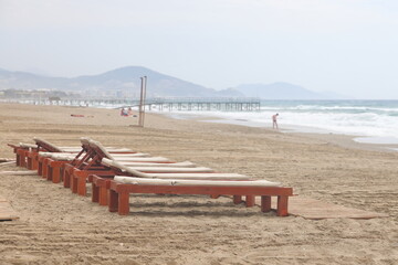 Beach with sun loungers in the rays of the setting sun on the turquoise Mediterranean Sea in Alanya, Turkey, April 2023.