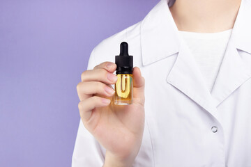 In the hand of a female doctor, a glass bottle with a pipette with an extract of CBD oil.  Alternative medical marijuana treatment.