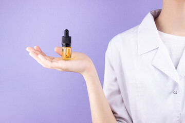 On the palm of a woman doctor is a glass bottle with a pipette with an extract of cbd oil. ...
