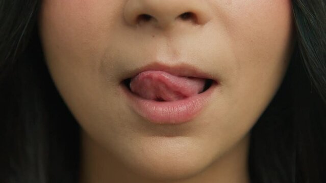 Attractive young girls lips and mouth, healthy skin face makeup. Closeup of sensual woman licking plump lips in slow motion smile 4K. Young woman face biting sexy lips and licking with tongue