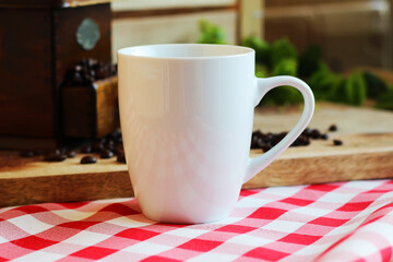 Blank white coffee mug on wooden background with coffee beans and vintage coffee grinder.