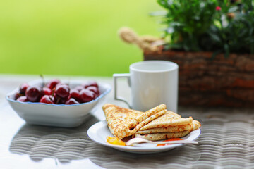 Fresh red cherry and traditional Russian pancakes and cup of coffee. breakfast at the garden