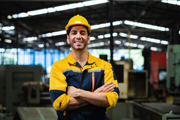 Portrait of smiling engineer standing with arms crossed in industrial factory. industrial concept...