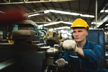 A male worker in a blue jumpsuit works in a metal lathe factory. The concept of working in a heavy metal industry factory.