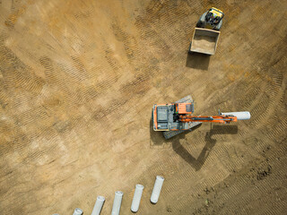 UAV view of an excavator seen taking part of a water pipe from a dumper truck. Seen ready to be dug...
