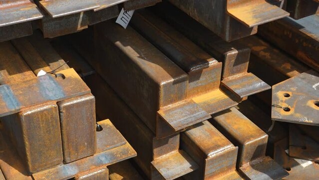 A stack of metal beams with welded elements in light rust