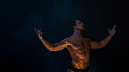 Fototapeta na wymiar A muscular athlete in an epic pose, fog and smoke on the background, warm mystical light from below, the concept of the antique beauty of the human body