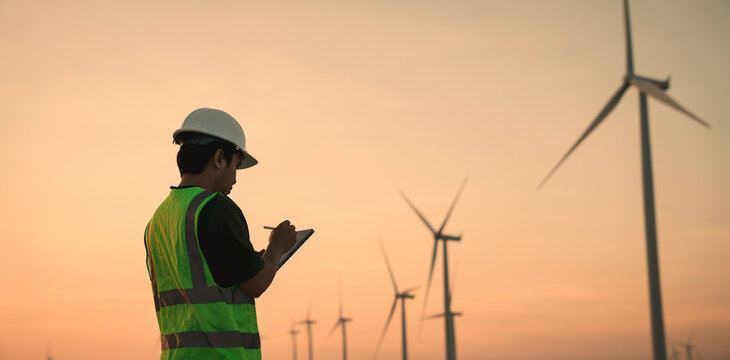 Service engineers checking system of windmill with tablet. Wind turbines generate electricity. Clean and Renewable energy concept.