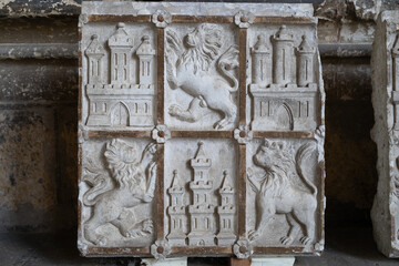 Vista de un bajorrelieve en piedra con la simbología de Castilla y León, España, leones y castillos.