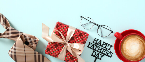 Happy Father's Day composition with vintage gift box, tie, glasses, sign Happy Fathers Day, red coffee cup on blue table.