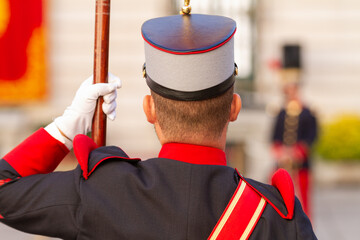 Vista de un soldado con uniforme antiguo portando una bandera en un desfile militar.