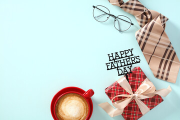 Happy Father's Day flat lay composition with vintage gift box, red coffee cup, necktie, glasses on blue table.