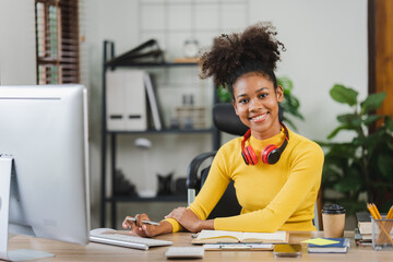 Young African American freelancer working on computer in home office. Female college student.