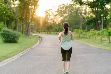 Fit Asian young woman jogging in park smiling happy running and enjoying a healthy outdoor lifestyle. Female jogger. Fitness runner girl in public park. healthy lifestyle and wellness being concept