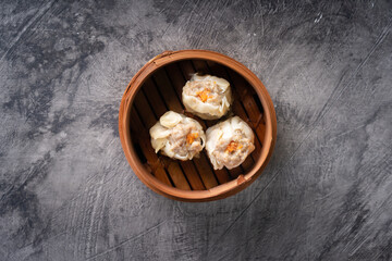 Chinese steamed dumplings or  Dim Sum in bamboo steamer on dark abstract background