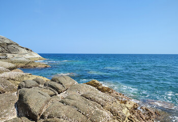 Fototapeta na wymiar Coast of the blue sea in the tropics with coastal large stones and blue sky, for posters, postcards