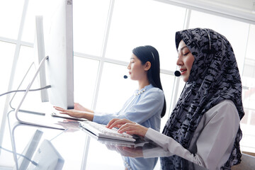 Smiling asian Muslim women is call center or secretary operator is wearing a headset and a...