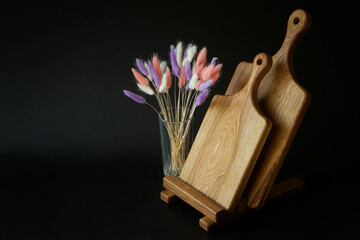 Wooden cutting boards from solid oak next to a multi-colored dried flower - lagurus italian on a...