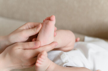 Mom massages the baby legs. Children massage.The concept of babysitting,maternity leave,masseur.Prevention of flat feet