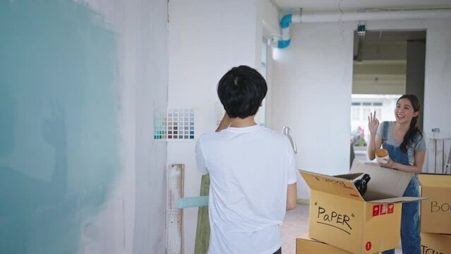 New home,Repair,happy,New life,insurance,carefree relationship,love lifestyle,renovation and decorating concept.Happy Young asian couple choosing blue color and painting walls at new apartment