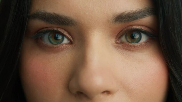 Close up of latino woman face. Attractive girl opening beautiful green, brown, hazelnut eyes. Brazilian young female model with big eyes looking at camera. Slow motion macro extreme close up 4K shot
