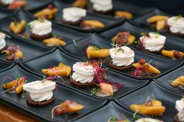 Obraz na płótnie Canvas Many prepared appetizers of feta cheese and rhubarb with sprout garnish arranged on black plates for a festive gourmet menu, selected focus