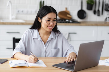 Happy female student using laptop computer, studying, distance learning or online education,...
