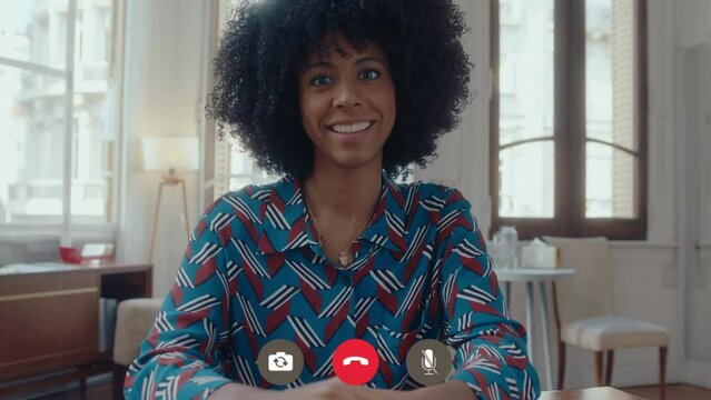Young African-American businesswoman sitting in the office at daytime, looking at camera and talking, having online meeting. Video call interface, POV shot