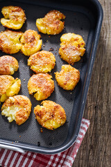 Baked potatoes in metal tray seasoned with rosemary and salt and pepper. Golden and crispy.