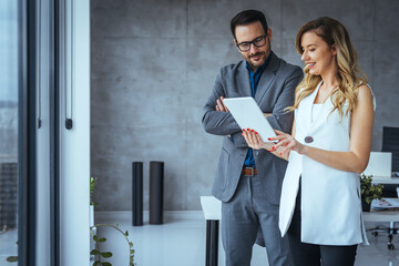 Two young businessman having a successful meeting in modern office. Business people having fun and chatting at workplace office. Image of two colleagues in office
