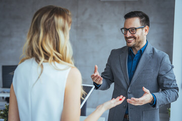 Image of two colleagues discussing about new project. Businessman and businesswoman in meeting using digital tablet and discussing business strategy. 