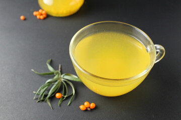 tea juice sea buckthorn yellow color in a cup and carafe on a black background with a place for text and copyspace. healthy vitamin drink tea
