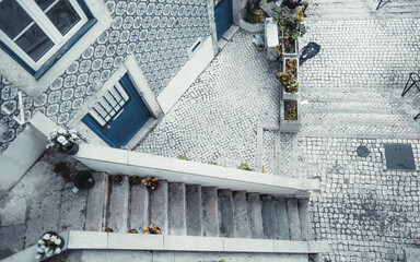 A high-angle shot in Lisbon captures a narrow staircase, guiding to a white cobblestone street....