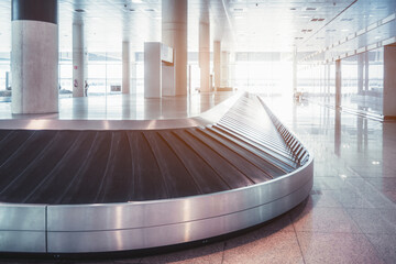 Barcelona Airport; Empty luggage claim area; Capturing the curved elbow of the conveyor belt with its lengthy stretch disappearing into the bright light in the background