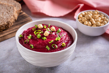 Beetroot hummus in a bowl, bread and chickpeas on the table