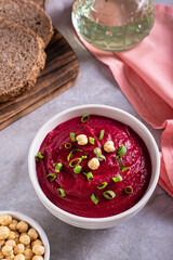 Bowl of vegetable beetroot hummus with chickpeas and herbs on the table vertical view