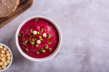 Beetroot hummus in a bowl, bread and chickpeas on the table top view