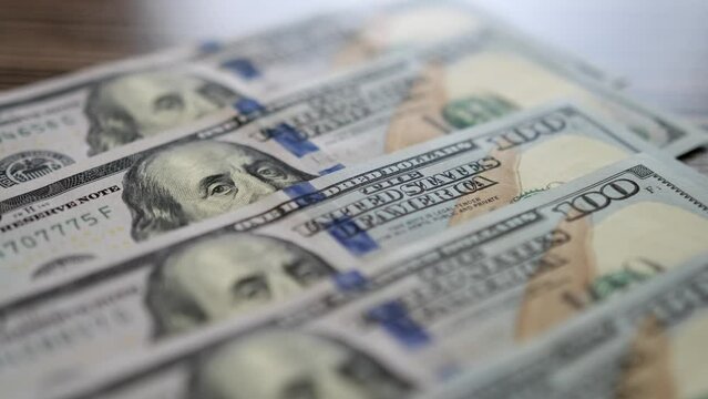 Close-up slow motion shot of 100 dollar bills lying flat on table. Background of money. Neat rows dollars money cash.
