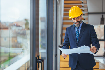 Portrait of an engineer holding a blueprint at a construction site while wearing a helmet....