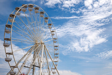 Ferris wheel an amusement park funfairs attraction with a cloudy blue sky - Powered by Adobe
